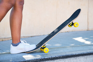 Fototapeta na wymiar Foot detail of young afro girl stepping on the tip of her skateboard against the ground