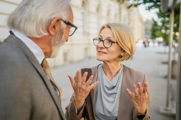 senor man and mature woman meet in city in sunny day talk old friends