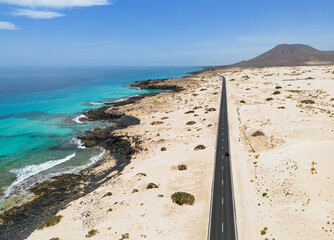Aerial mid level panoramic view of the road between the coast and Parque Natural sand dunes heading out of Corralejo Fuerteventura Spain