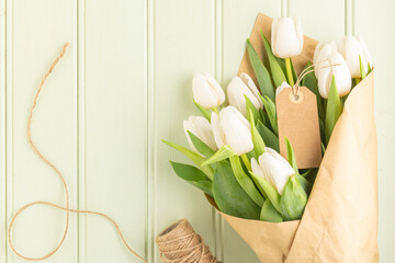 Bouquet of white tulips on a green wooden background, copy space. Easter. Top view