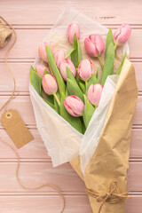 Pink tulip flowers bouquet on pale pink wooden background. Flat lay, top view. Spring floral concept.