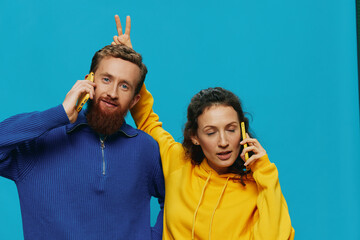 Woman and man cheerful couple with phones in their hands crooked smile cheerful, on blue...