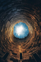 Looking up from inside a well at a small circle of sky, holy light. AI generative