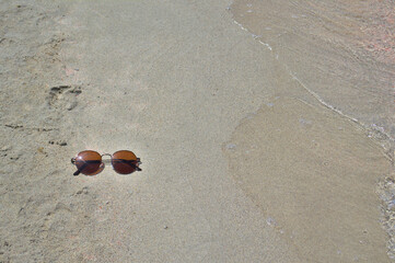 Sunglasses on a sandy beach by the water