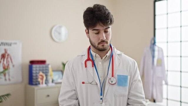 Young hispanic man doctor saying no with head at clinic