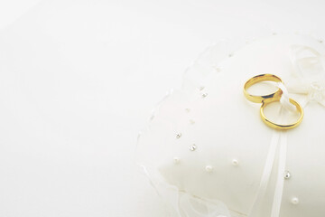Gold wedding rings on white ring pillow with copy space focus on rings