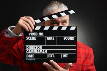 Senior actor with clapperboard on black background. Film industry