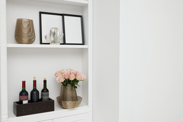 Shelves with different decor near white wall, space for text. Interior design