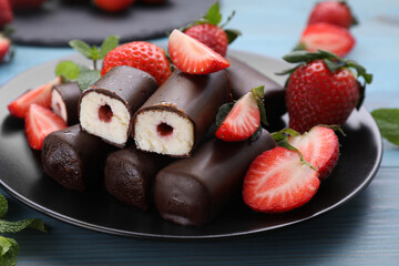 Delicious glazed curd snacks with fresh strawberries and mint on light blue wooden table, closeup
