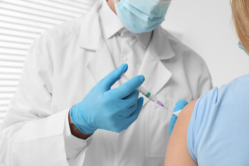 Doctor giving hepatitis vaccine to patient in clinic, closeup