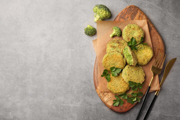 Delicious vegan cutlets with broccoli, parsley and cutlery on light gray table, flat lay. Space for text