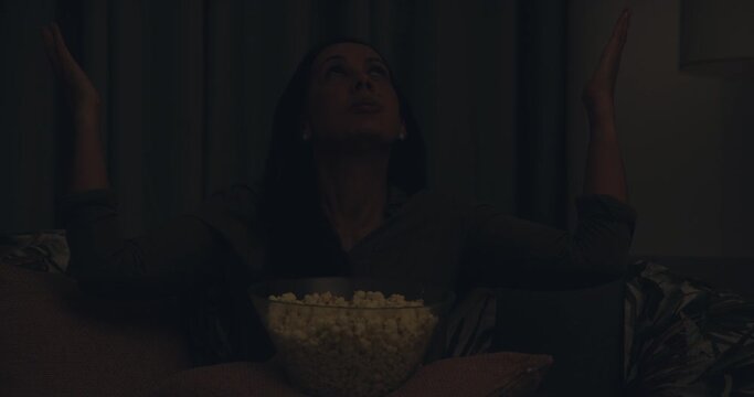 Woman, watching tv and blackout at night in power outage relaxing on living room sofa at home. Upset, annoyed or frustrated female person and lights off during entertainment or electricity failure