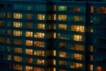Fototapeta na wymiar Late afternoon windows of a high rise office building with flashing and illuminating inside lighting. airborne top view