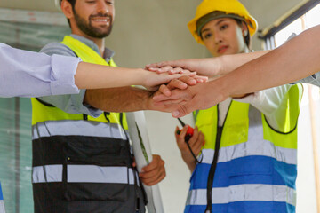 Hand focus. Male and female architect engineer team wearing safety gear shaking hands, congratulating, talking, consulting at construction site.