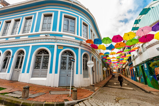 Tourist walks down a street decorated with colorful umbrellas in Bogota, Colombia
