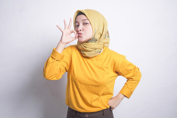 Portrait of beautiful muslim woman wearing orange t-shirt, smiling doing okay sign with hand