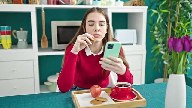 Young hispanic woman having breakfast using smartphone at dinning room