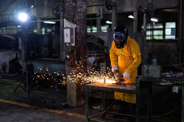 Welder with Torch Protective Helmet and leather suit in big hall welding metal and fire spark
