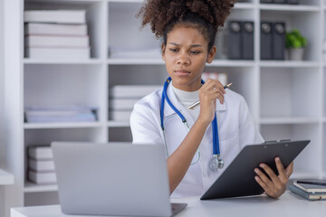 Happy doctor Portrait of young African American woman nurse or doctor smilingusing a laptop writing content at consultation