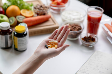 Woman professional nutritionist checking dietary supplements in hand, surrounded by a variety of fruits, nuts, vegetables, and dietary supplements on the table - 606939726