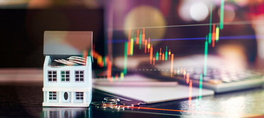 House model and stock market graph on table. Real estate and investment concept.