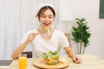 Obraz na płótnie Canvas Lifestyle in living room concept, Young Asian woman eating vegetable salad and orange juice