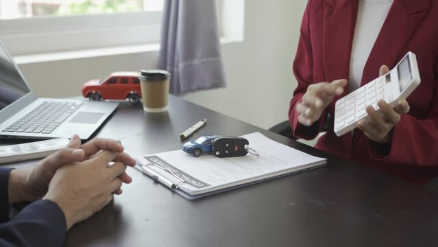 Asian female employee signing a car insurance document or a rental contract or agreement. Buy or sell a new or used car with car keys on table with handshake. 4k video