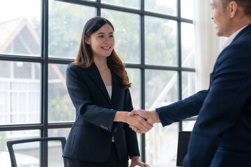 Happy young Asian businesswoman and businessman handshake to congratulate success. Successful Asian business people working together team.