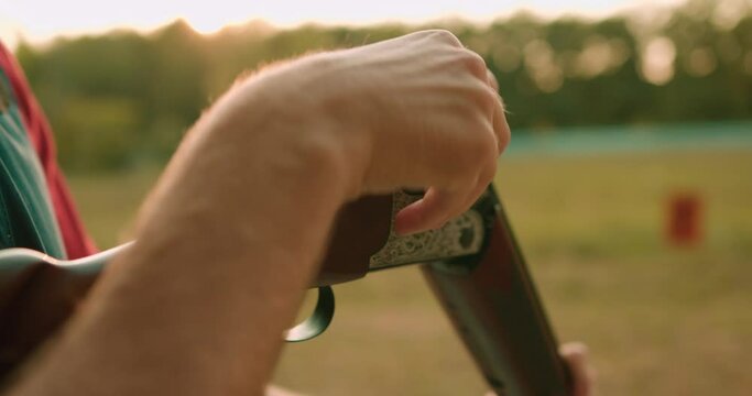 young man loading bullets in to magazine in slow motion, cropped video. Hunter loading bullet to carbine with optical-sight. Bullet shell. preparation for shooting Autumn hunting season.