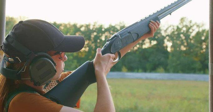 Young man putting a cartridge into his gun, cocking it, aiming and firing at a wobble range. woman looking up focusing on a tiny target. girl learn how to shoot shotgun a improve bird hunting skills