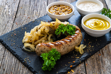 Grilled white sausages with onion on wooden table
