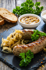 Grilled white sausages with onion on wooden table
