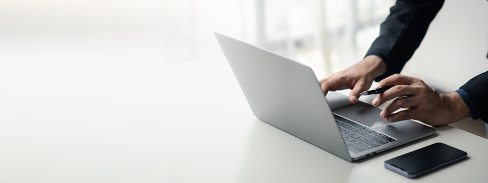 Person typing on laptop keyboard, businessman working on laptop, he is typing messages to colleagues and making financial information sheet to sum up the meeting.