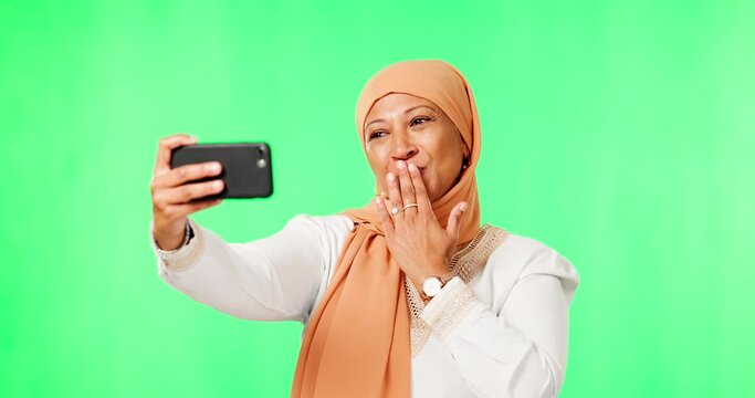 Islamic woman, selfie and green screen with kiss, studio background or happy in social media mock up. Female muslim model, influencer and photography with sign, emoji and profile picture in mockup