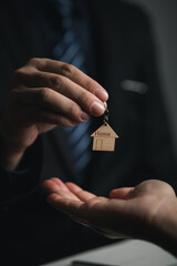 A home rental company employee is handing the house keys to a customer who has agreed to sign a rental contract, explaining the details and terms of the rental. Home and real estate rental ideas.