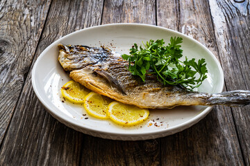 Grilled sea bream and vegetables on wooden table
