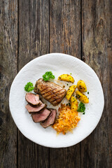 Grilled pork loin steaks with fried potatoes and sauerkraut salad on wooden table
