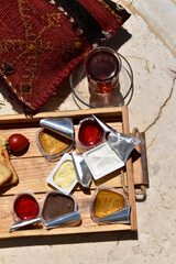 Fototapeta na wymiar cup of tea and wooden tray with small portions of honey, jam, butter and cherry tomato, top view