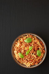Homemade Tomato Basil Sausage Spaghetti in a Bowl on a black background, top view. Flat lay, overhead, from above. Space for text.