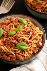 Homemade Tomato Basil Sausage Spaghetti in a Bowl on a black background, low angle view.