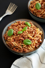 Homemade Tomato Basil Sausage Spaghetti in a Bowl on a black background, side view.
