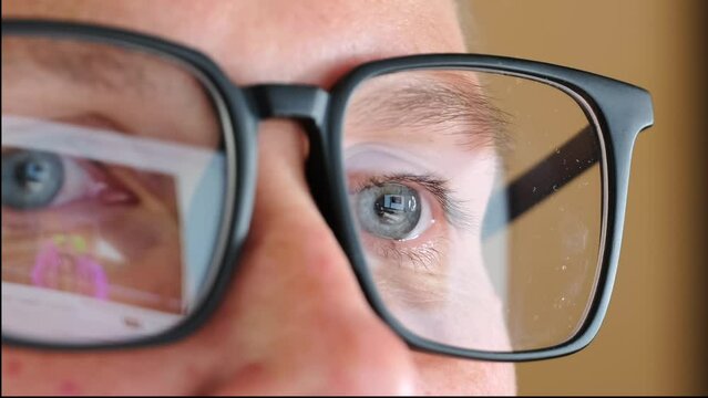 Close up human eyes in optical glasses look at monitor screen. Women's blue eyes in glasses look at image on the computer. Process of working in front of devices.