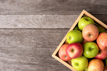 Red and green apple in wooden crate isolated on rustic wooden table background with copy space, top view, flat lay.