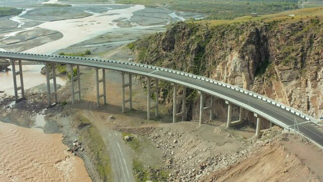 Flyover with highway bridge spanning across river capturing beautiful mountain landscape.