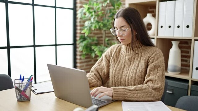 Young beautiful hispanic woman business worker stressed using laptop working at office