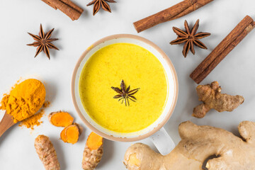 Turmeric drink, latte, tea, golden milk with cinnamon, ginger and anise in a mug on white background