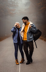 Portrait of couple spending time together walking on forest road on a foggy morning.