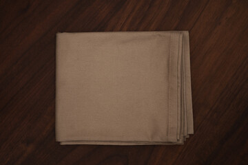 cloth beige napkin on walnut wood table