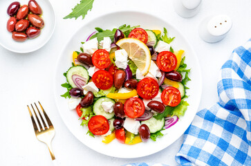 Traditional greek salad with feta cheese, kalamata olives, tomatoes, paprika, cucumber and onion, healthy mediterranean diet food. White table background, top view