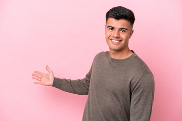 Young caucasian handsome man isolated on pink background extending hands to the side for inviting to come